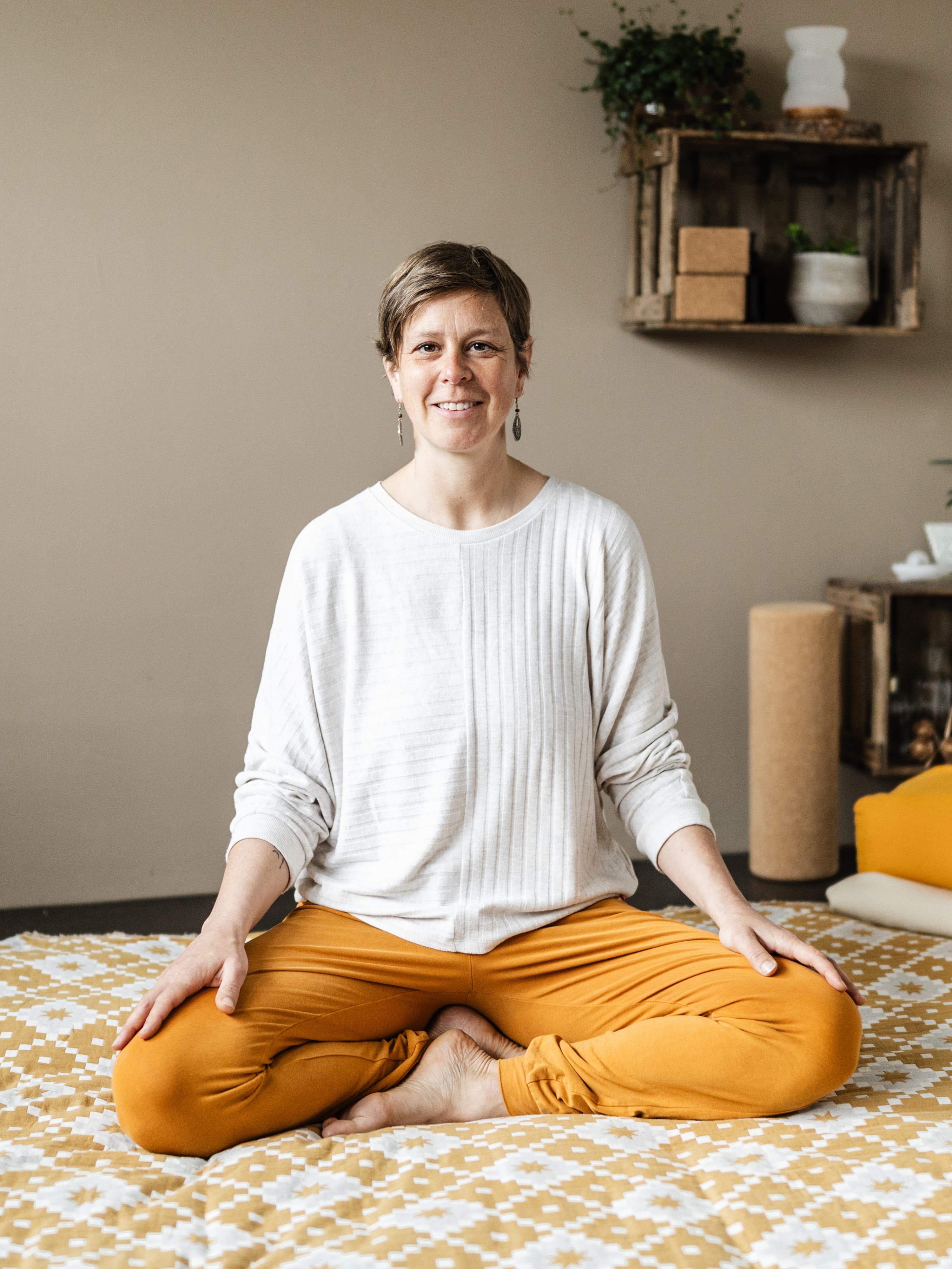 Anne Thorand, Embodiment Coach und Yogalehrerin aus dem Breisgau, lachend im Schneidersitz