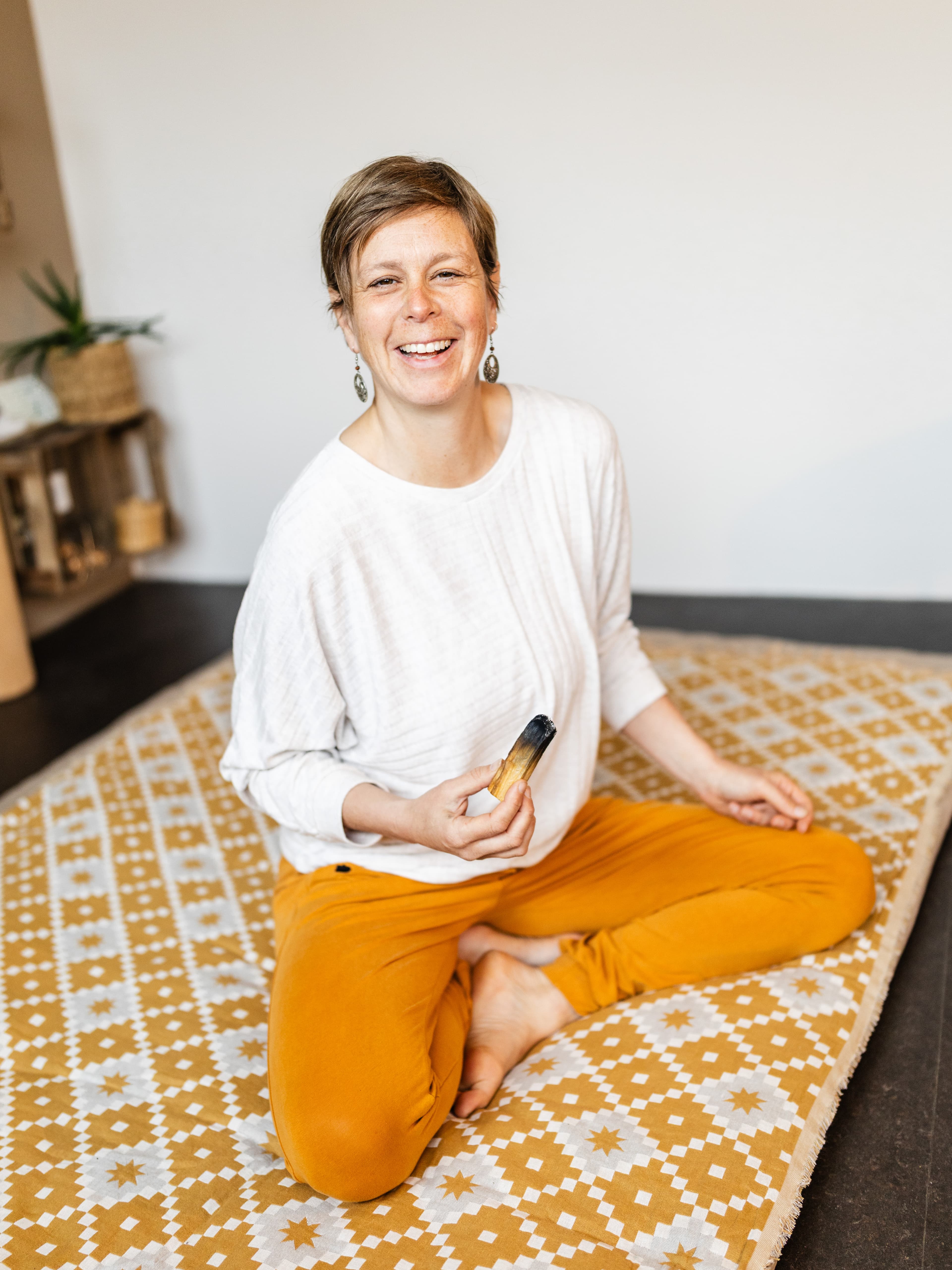 Anne Thorand, Embodiment Coach und Yogalehrerin aus dem Breisgau, lachend im Schneidersitz