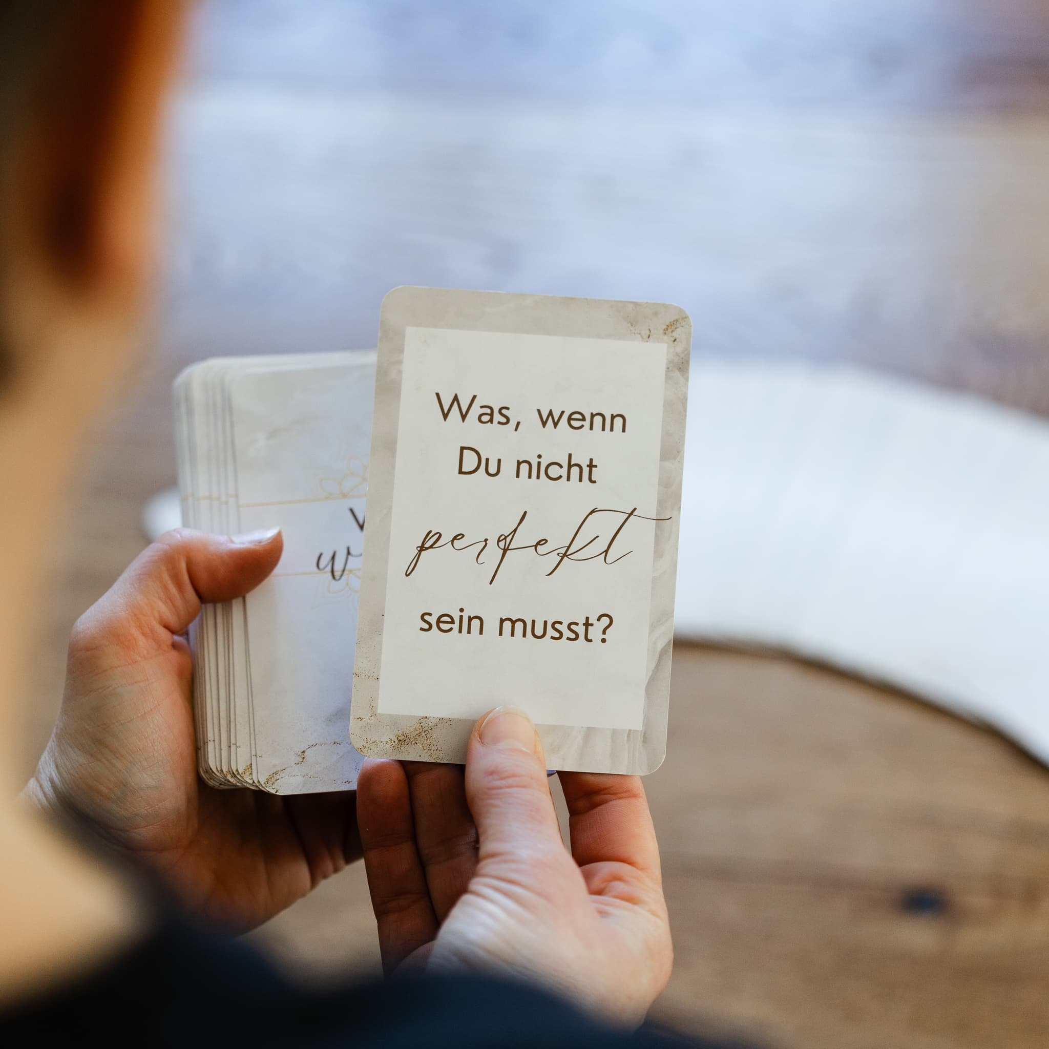 Hand hält Iffirmationskarte mit der Frage "Was, wenn Du nicht perfekt sein musst?" – Reflexionskarten für Coaching und Selbstentwicklung